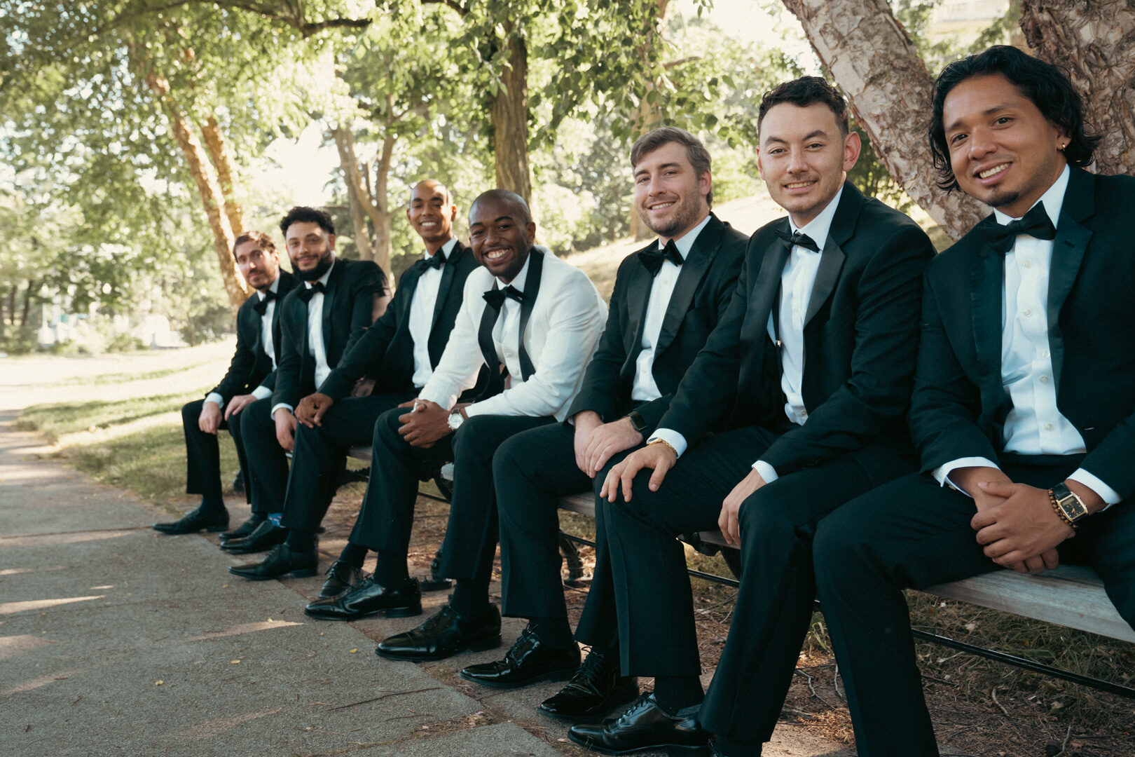 Groomsmen in black tuxedos seated together before the wedding