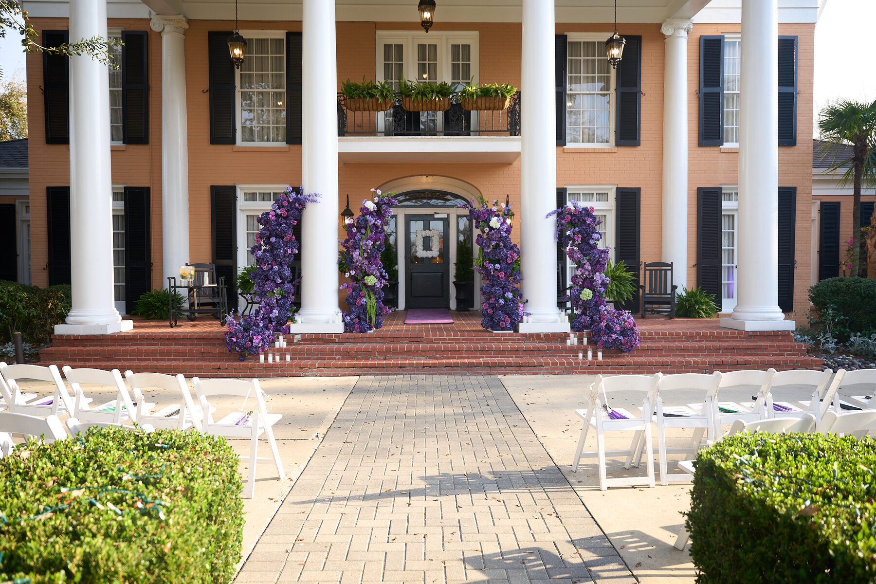 Historic mansion wedding venue decorated with purple floral arches