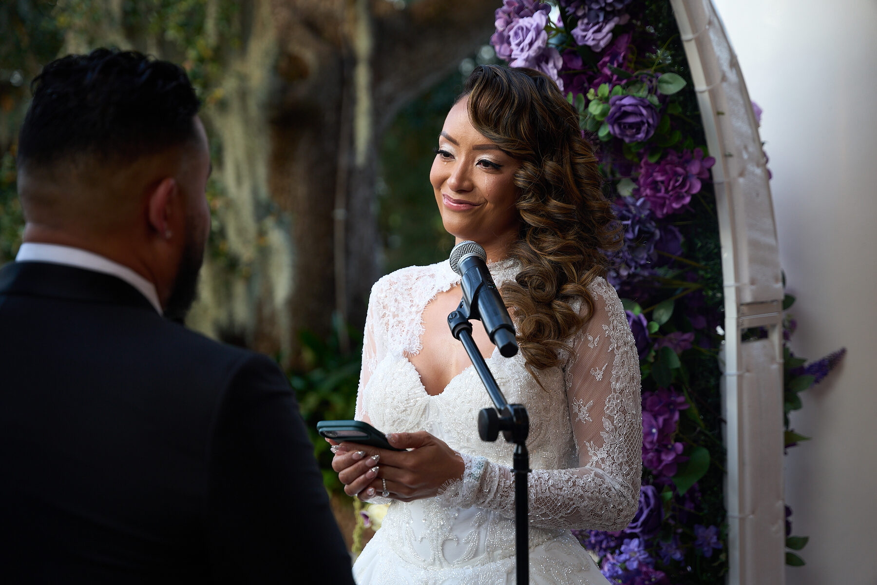 Bride reading her wedding vows into a microphone during ceremony