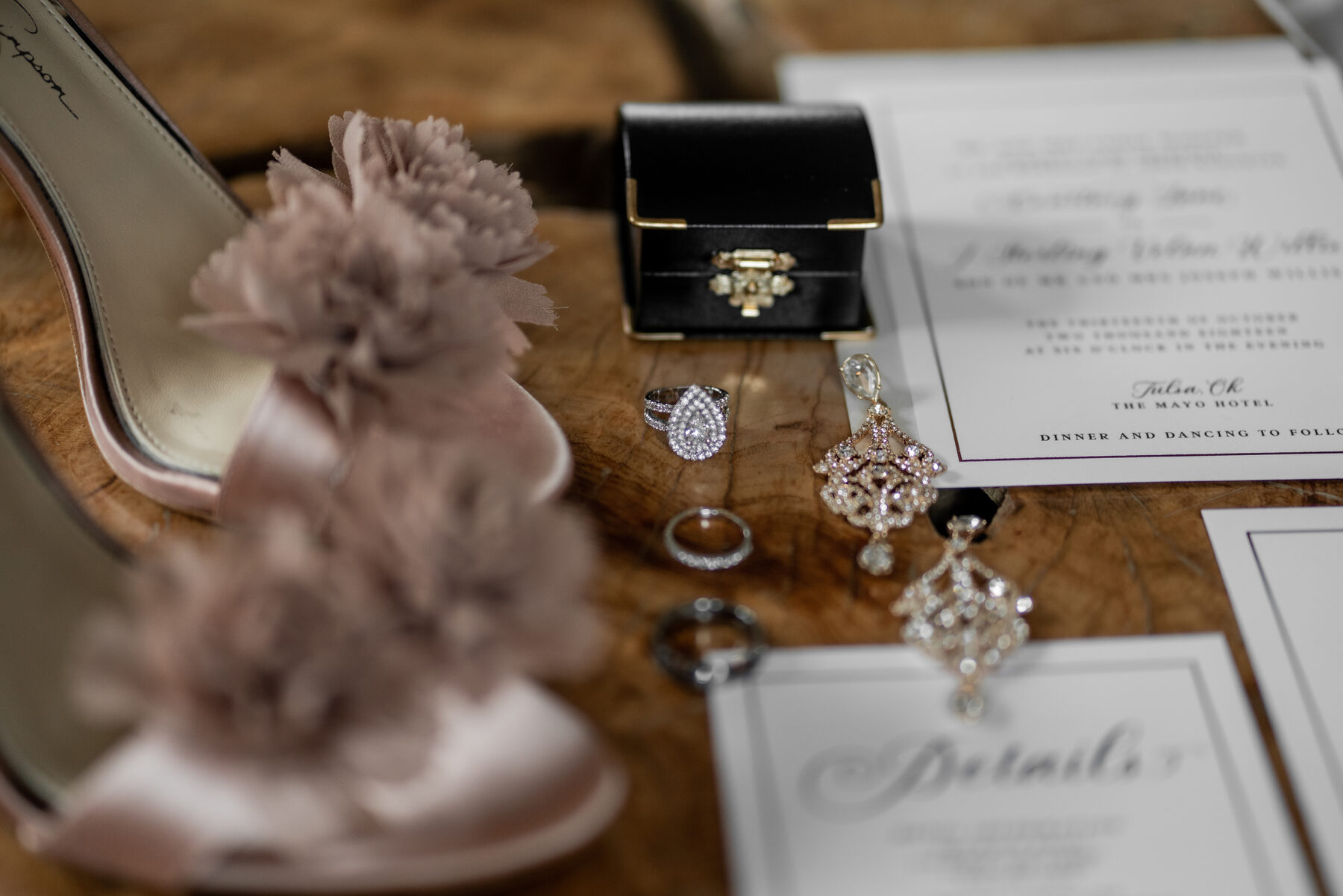Wedding ring, earrings, and invitation suite flat lay detail shot