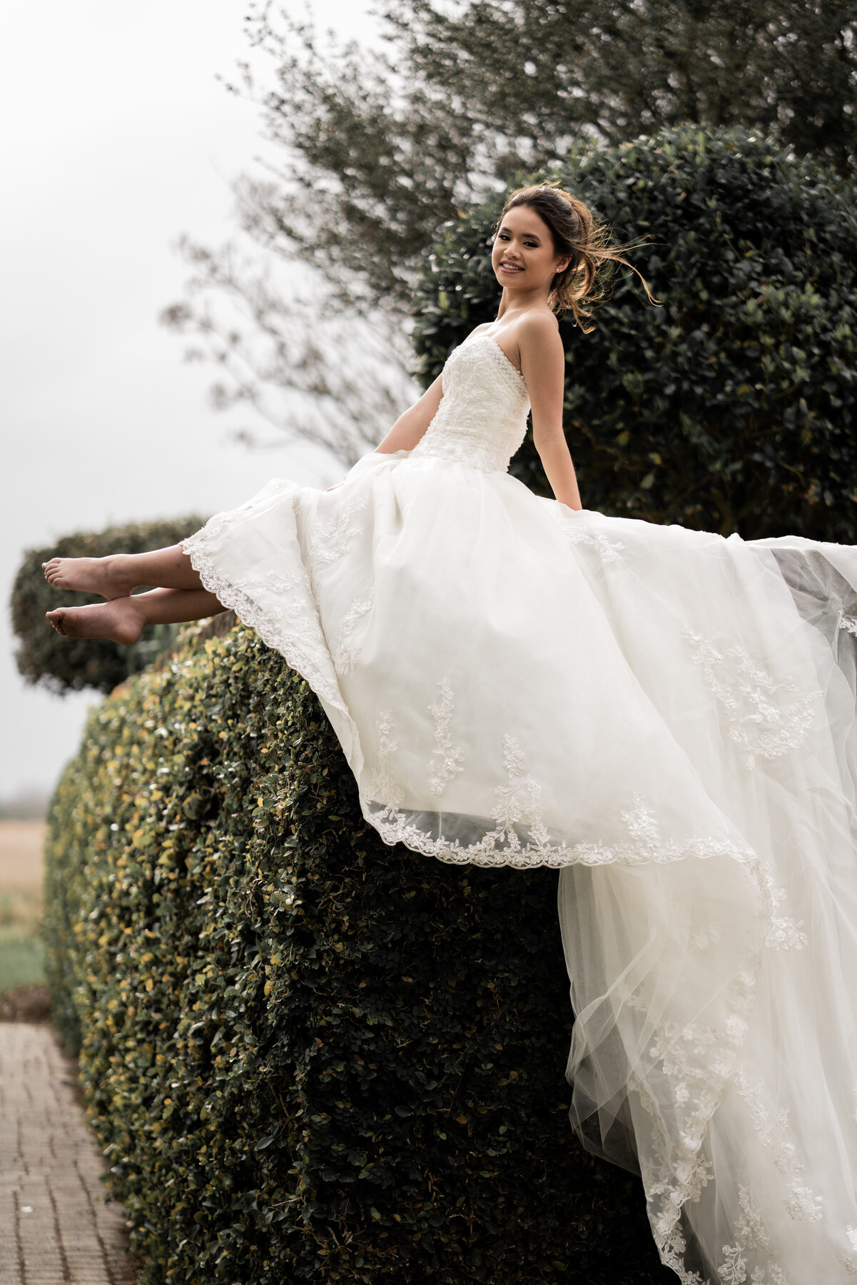 Bride in strapless ball gown laughing outdoors, luxury wedding portrait